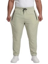 Frontaal beeld van een man die een lichtgroene sportbroek met zwarte ritssluitingen en trekkoord toont, met witte sneakers.