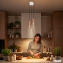 Vrouw snijdt groenten in een keuken met drie koperkleurige hanglampen boven het aanrecht.