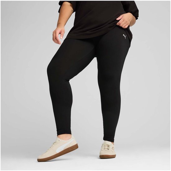 Een voller postuur vrouw in zwarte PUMA legging en beige sneakers, hurkend.