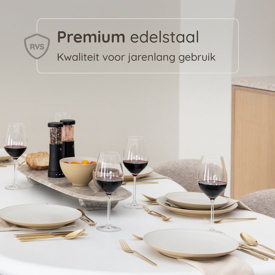 Gouden bestek op een gedekte tafel met wijnglazen en eten.
