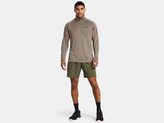 Man met lange mouwen, grijze halve rits trui en legergroene shorts