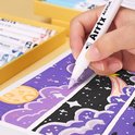 Gedetailleerde close-up van een hand die met een Arrtx acrylmarker een paarse tekening maakt.