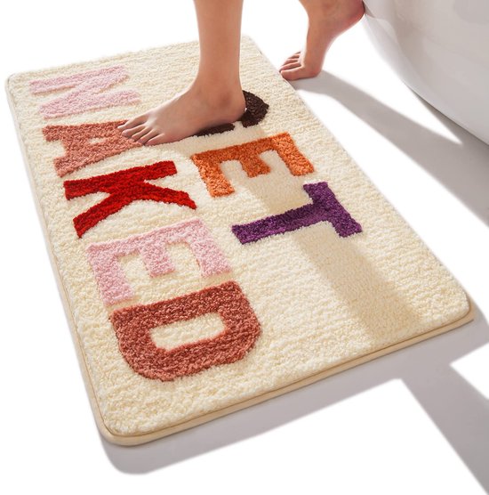 Beige pluche badmat met de tekst 'GET NAKED' in veelkleurige letters. Een voet stapt op de mat.