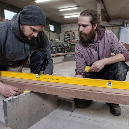 Twee mannen gebruiken een gele Stabila waterpas van 120 cm op een houten balk.