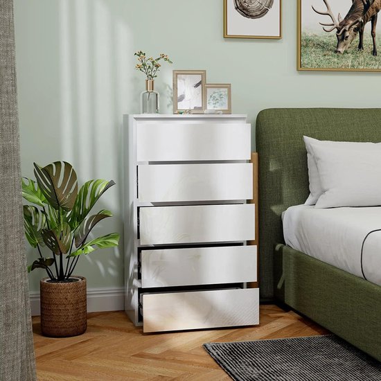 Witte ladekast met vijf laden, deels open, naast een bed.