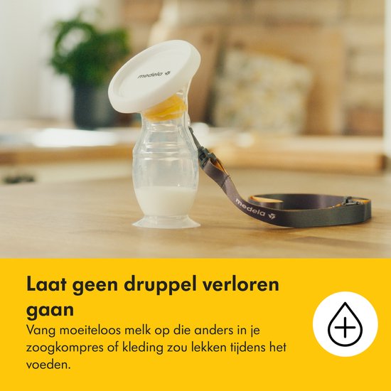 Medela melkcollector met nekkoord op een houten tafel, bevat witte vloeistof.