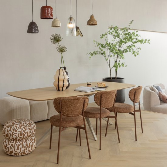 Table à manger avec trois fauteuils marron et deux poufs empilés à motif graphique.