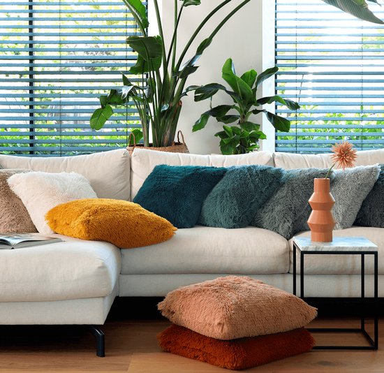 Un canapé blanc avec divers coussins fluffy jaune ocre, bleu profond, vert, gris et beige.