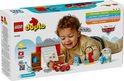 Een jongetje speelt met LEGO Duplo Cars. Hij heeft de rode Lightning McQueen auto, Doktersgarage en andere accessoires.