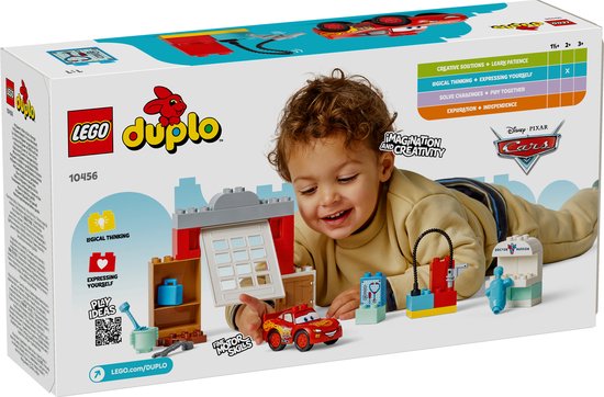 Een jongetje speelt met LEGO Duplo Cars. Hij heeft de rode Lightning McQueen auto, Doktersgarage en andere accessoires.