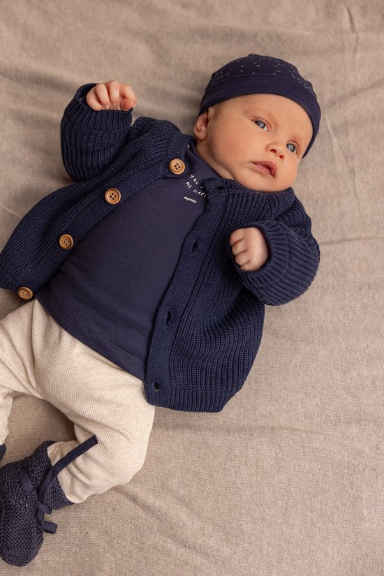 Baby in donkerblauw longsleeve shirt met opdruk en bijpassende muts.
