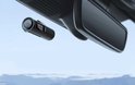 AZDome dashcam gemonteerd aan de voorruit, nabij de achteruitkijkspiegel, met wazige bergen op de achtergrond.