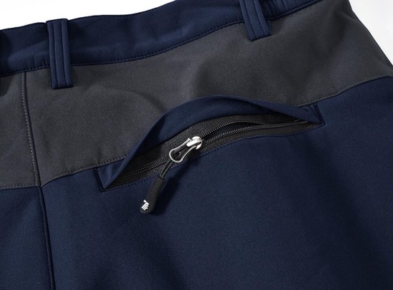 Sluiting van een opgezette zak met rits, aan de zijkant van een donkerblauwe outdoorbroek met grijs vlak.