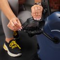 Close-up van een hand die de pedaalband van een hometrainer aanpast.