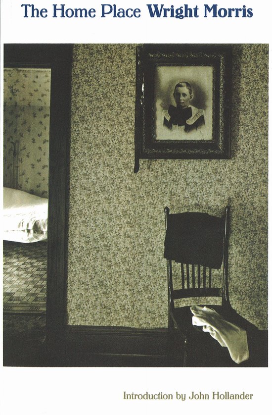 Boekhoes met de titel 'The Home Place Wright Morris'. Een antieke lijst met een kinderfoto hangt aan een behangen muur met bloemenpatroon. Een stoel met een doek staat ervoor.