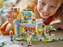 Fille jouant avec un set LEGO Friends de boutique d'accessoires pour animaux, aux couleurs rose, jaune et bleu.