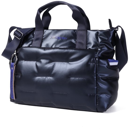 Zijaanzicht van de donkerblauwe, glanzende, gewatteerde tas met handvatten en schouderband.