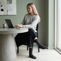 Vrouw op laptop met donkergrijze sokken met bruine streepjes.