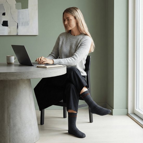 Vrouw op laptop met donkergrijze sokken met bruine streepjes.