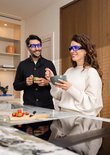 Man en vrouw met brillen eten in een moderne keuken.