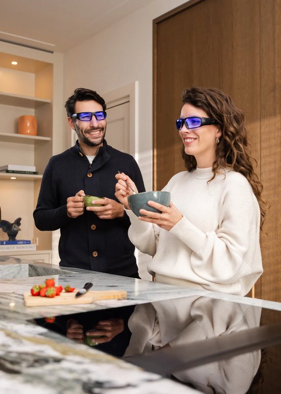 Man en vrouw met brillen eten in een moderne keuken.