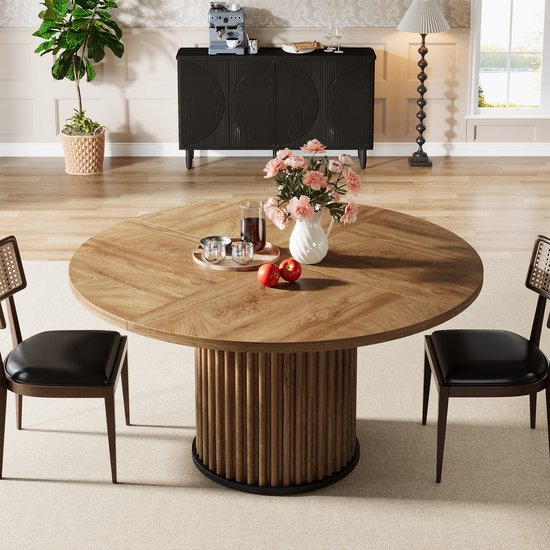 Ronde houten eettafel met een gedetailleerd onderstel, versierd met bloemen en fruit.