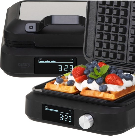 Open zwart wafelijzer met twee wafels versierd met slagroom, aardbeien en bosbessen.