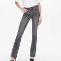 Model in een lichtgrijze flared jeans, met de handen in de zakken.