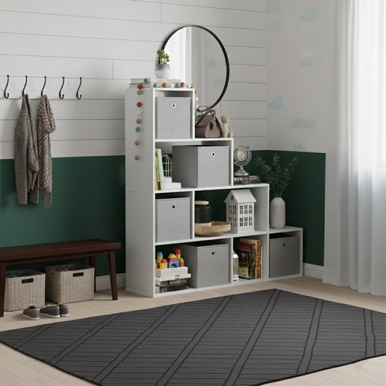 Witte trappenkast met zes vakken, gevuld met grijze opbergdozen, boeken en decoraties, in een kamer met groene en witte wanden.