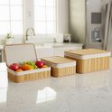 Drie naturel bamboe opbergmanden met fruit en brood in een keuken.