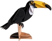 Toucan en papier 3D noir avec grand bec jaune et noir, assis sur un socle en bois.