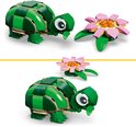 Groene schildpad en roze waterlelie, gemaakt van LEGO-stenen. De schildpad heeft grote ogen en een bruine onderkant.