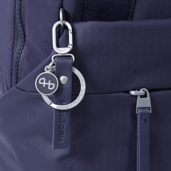 Sleutelhanger met Hedgren logo aan een donkerblauwe rugzak.
