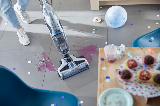 BISSELL Crosswave C3 Select stofzuiger met dweil reinigt gemorste drank en confetti op tegelvloer.
