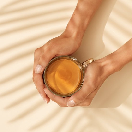 Une tasse d'espresso tenue par deux mains.