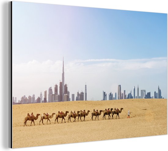 Wanddecoratie Metaal - Aluminium Schilderij Industrieel - Kudde kamelen in de woestijn en op de achtergrond de Burj Khalifa en Dubai - 180x120 cm - Dibond - Foto op aluminium - Industriële muurdecoratie - Voor de woonkamer/slaapkamer