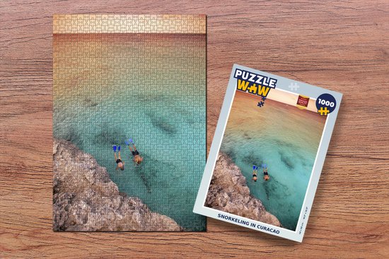 Puzzle de 1000 pièces avec deux personnes faisant du snorkeling et un morceau de la boîte, sur fond de bois.