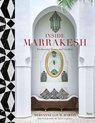 Boekomslag 'Inside Marrakesh: Enchanting Homes and Gardens' met een rieten bank en kussens, een spiegel en vazen.