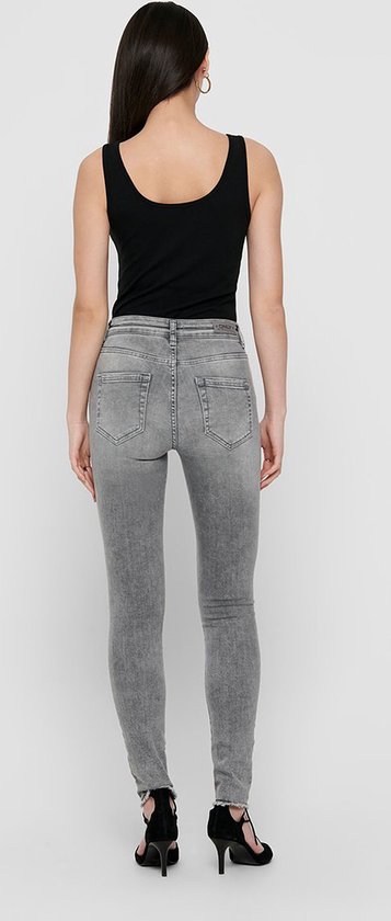 Achterkant van model in een zwarte tanktop en grijze skinny jeans.