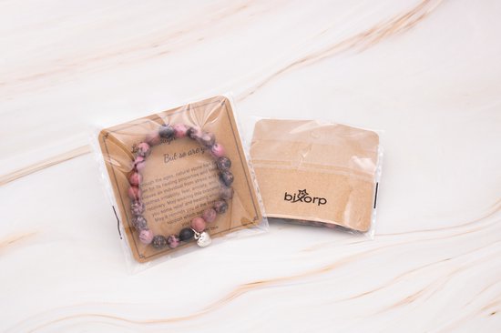 Roze en bruine kralenarmband met hartvormige hanger, verpakt op kaart.