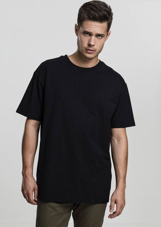 Man, vooraanzicht, draagt een donkergrijs oversized T-shirt met korte mouwen.