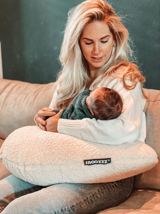 Vrouw met baby op schoot, rustend op een beige voedingskussen met teddy stof.