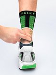 Close-up van een Falke sportsok met groene noppen, die een proefpersoon aantrekt.