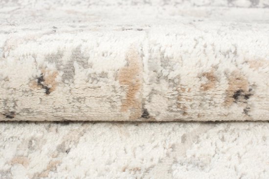 Gros plan de la texture d'un tapis vintage beige clair avec des accents gris et marron.