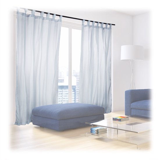 Lichtgrijze, doorschijnende gordijnen met lussen in een woonkamer met blauw meubilair.