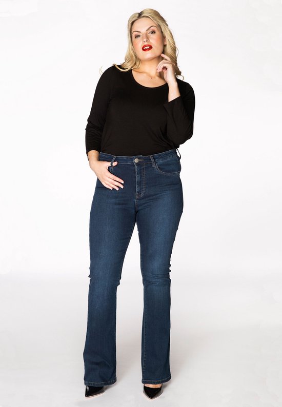 Vrouw met blond haar, vooraanzicht, draagt een zwarte top en een donkerblauwe flare jeans.
