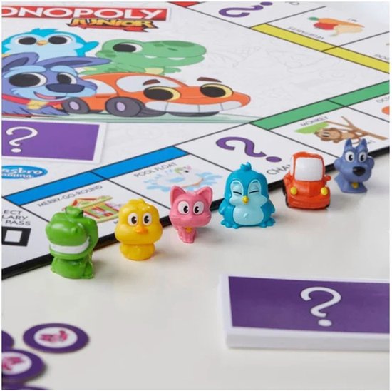 Speelstukken voor Monopoly Junior (krokodil, kip, kat, pinguïn, auto, hond) op het speelbord.