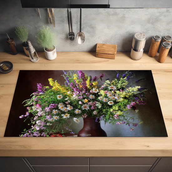 Een bruin aardewerk vaas gevuld met een boeket van witte madeliefjes, paarse lavendel, gele bloemen en groene takken op een donkerbruine achtergrond.