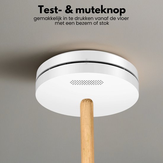 Witte rookmelder aan het plafond, bediend met een bezemsteel via de testknop.