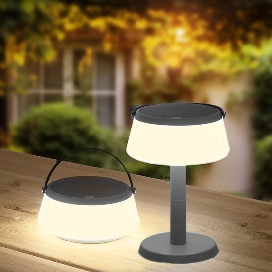 Une lampe portable allumée et tamisée avec poignée et une lampe sur pied avec base sur une table en bois.